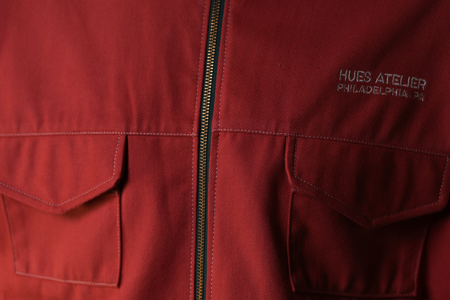 Red jacket with a zipper and 'Hues Atelier Philadelphia PA' branding.